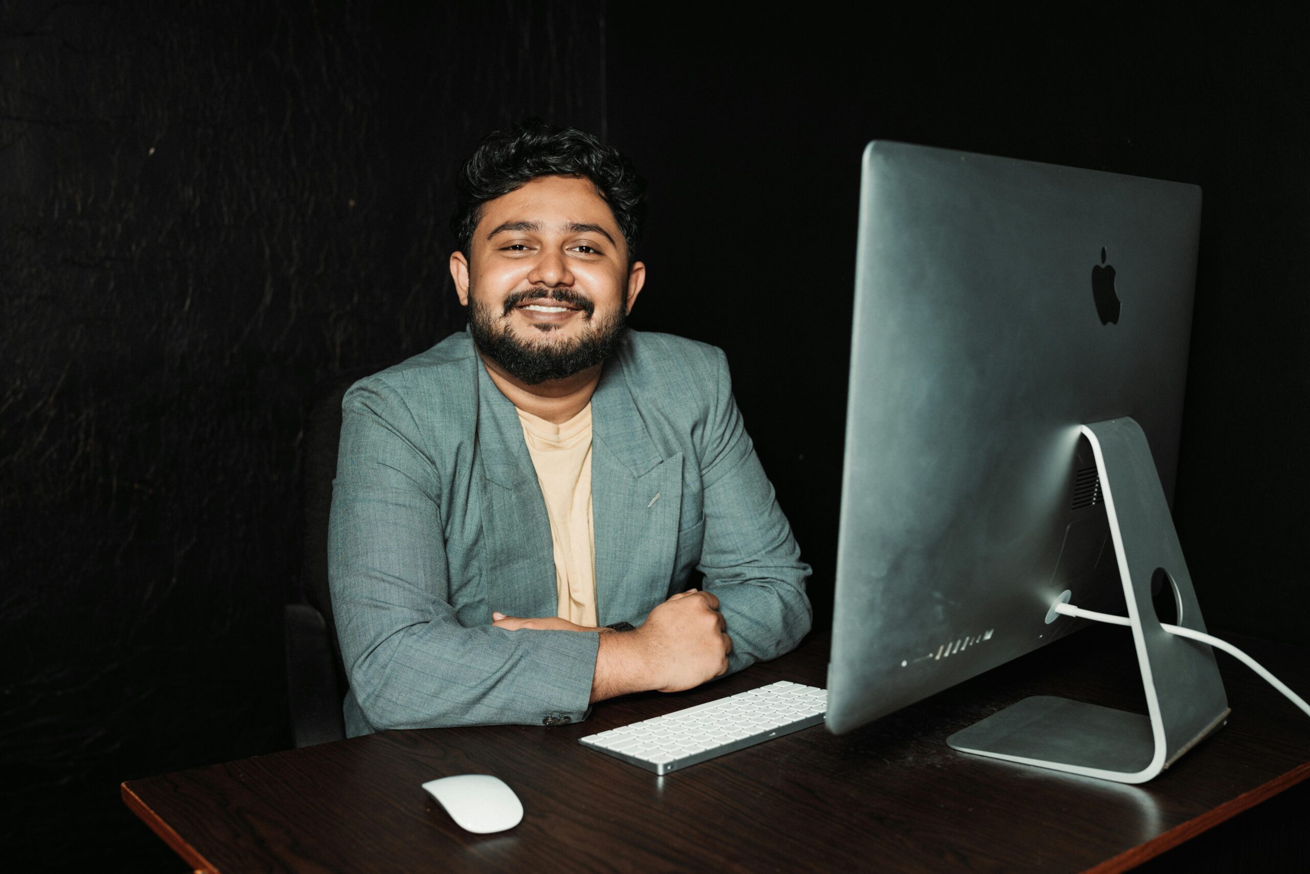 Confident businessman sitting at desk, working on computer in modern office.